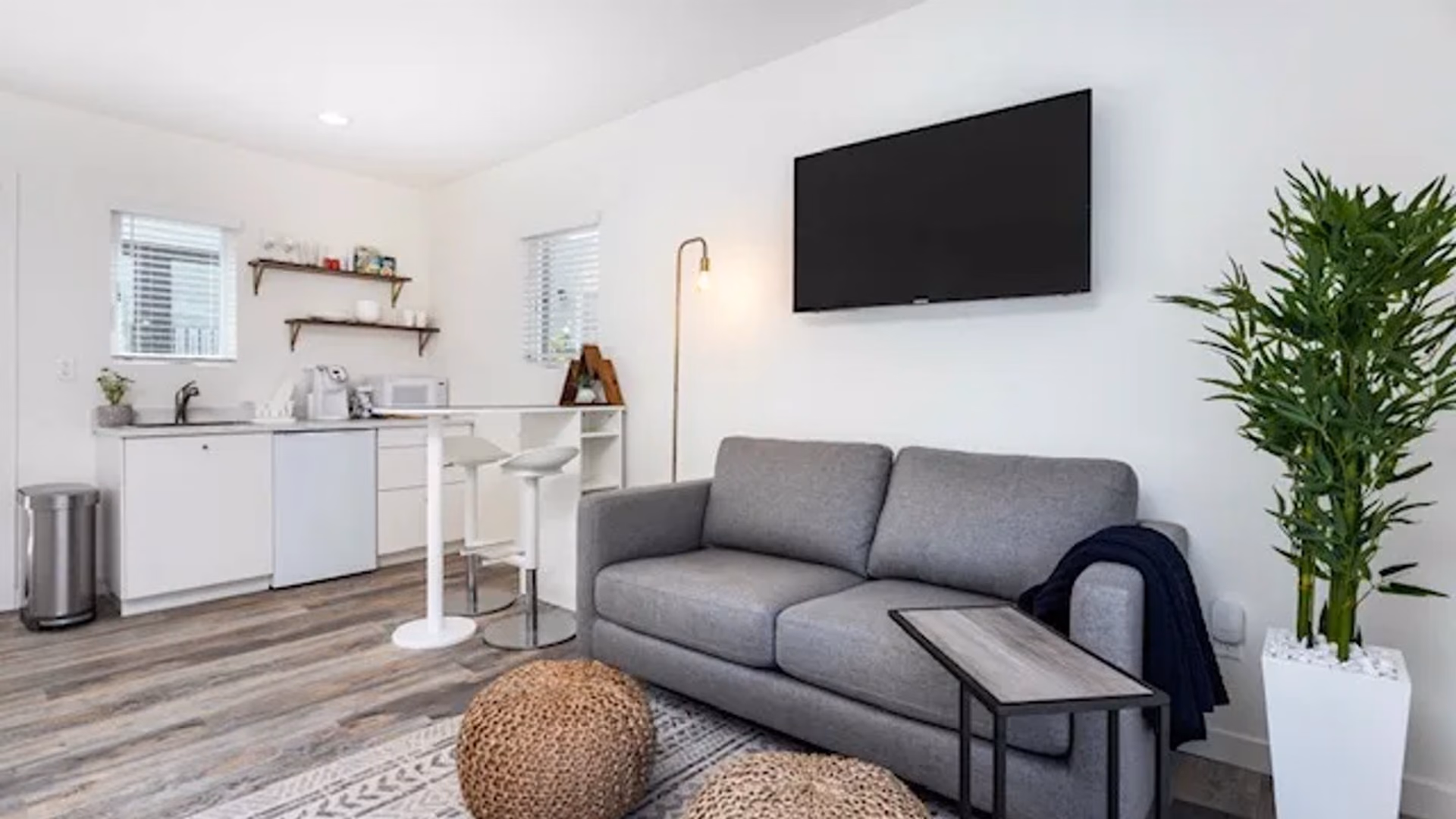 Finished garage conversion in use as a living suite, with a sitting area, a compact kitchenette along the back wall, and wood-look flooring